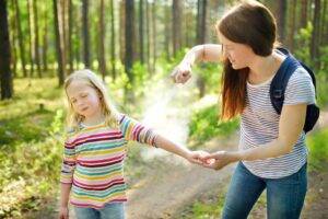 mother-spraying-daughter-for-bug-bites-prevention