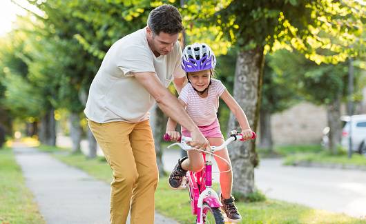 Summer-Happy Father Teaching His Little Daughter To Ride A bike