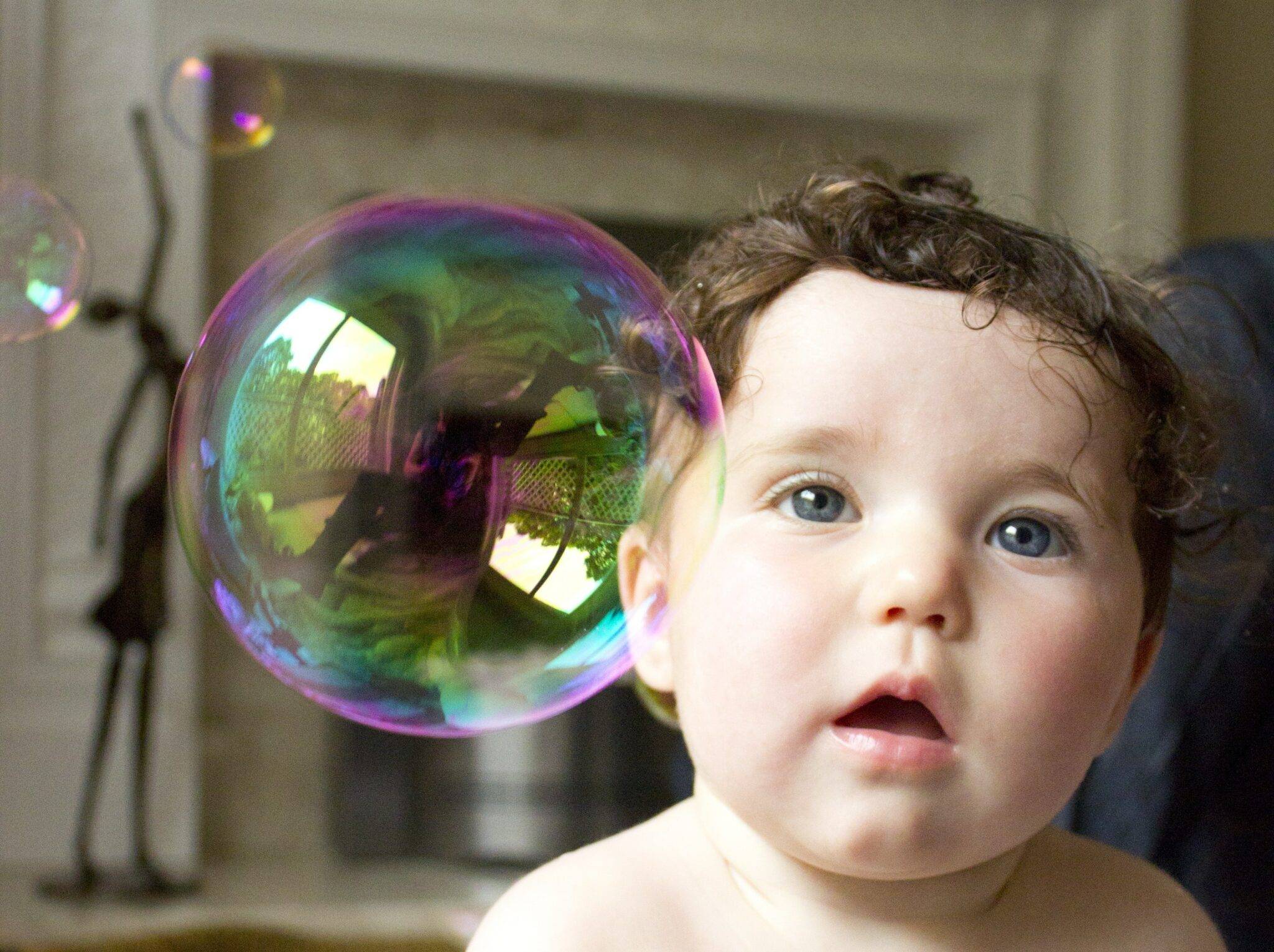 newborn baby doctor amazed child playing with bubbles scaled